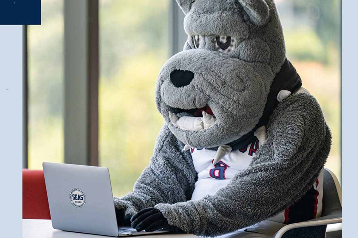 The costume mascot of Gonzaga university sits at a laptop computer